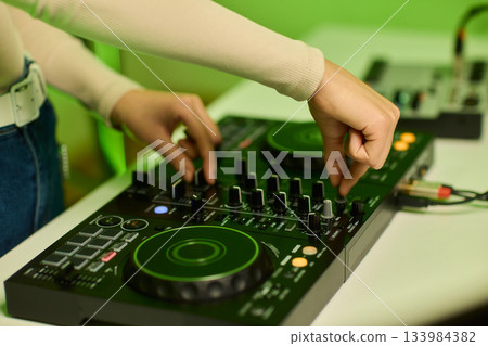 DJ setup overview, Energetic club DJ performing with digital controller in action, Content creator mixing music live using digital turntables under vibrant stage lights DJ setup overview, Energetic club DJ performing with digital controller in action, Content creator mixing music live using digital turntables under vibrant stage lights 133984382