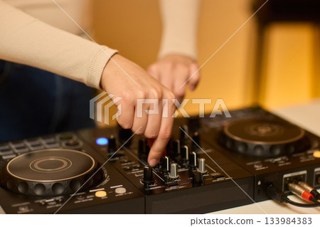 DJ setup overview, Energetic club DJ performing with digital controller in action, Content creator mixing music live using digital turntables under vibrant stage lights DJ setup overview, Energetic club DJ performing with digital controller in action, Content creator mixing music live using digital turntables under vibrant stage lights 133984383