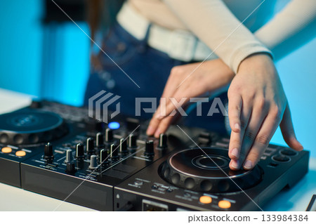 DJ setup overview, Energetic club DJ performing with digital controller in action, Content creator mixing music live using digital turntables under vibrant stage lights DJ setup overview, Energetic club DJ performing with digital controller in action, Content creator mixing music live using digital turntables under vibrant stage lights 133984384