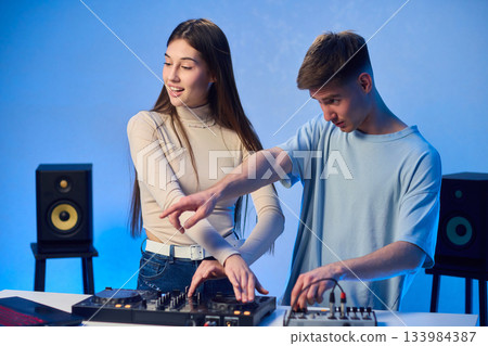 Music creators in studio, Studio session featuring musical synthesis and focused teamwork, Electronic music producers working together with various tools and instruments Music creators in studio, Studio session featuring musical synthesis and focused teamwork, Electronic music producers working together with various tools and instruments 133984387