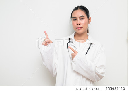 Woman Doctor with Stethoscope in White Uniform on Plain Background Pointing Finger 133984410