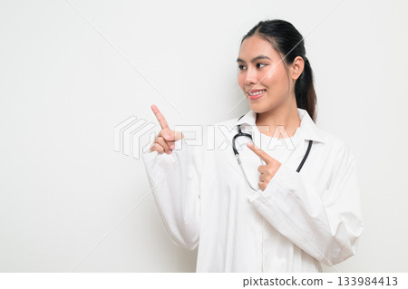Woman Doctor with Stethoscope in White Uniform on Plain Background Pointing Finger 133984413