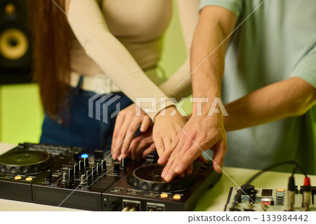 DJ setup overview, Energetic club DJ performing with digital controller in action, Content creator mixing music live using digital turntables under vibrant stage lights 133984442