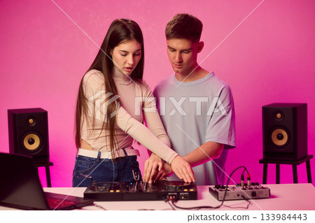 Music creators in studio, Studio session featuring musical synthesis and focused teamwork, Electronic music producers working together with various tools and instruments Music creators in studio, Studio session featuring musical synthesis and focused teamwork, Electronic music producers working together with various tools and instruments 133984443