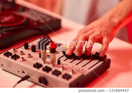 Closeup of tactile controls and vibrant patch cords in studio, Adjusting analog sequencing equipment with bright cables and warm ambient lighting in home studio 133984447