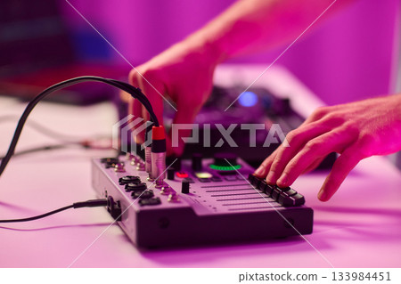 Closeup of tactile controls and vibrant patch cords in studio, Adjusting analog sequencing equipment with bright cables and warm ambient lighting in home studio 133984451