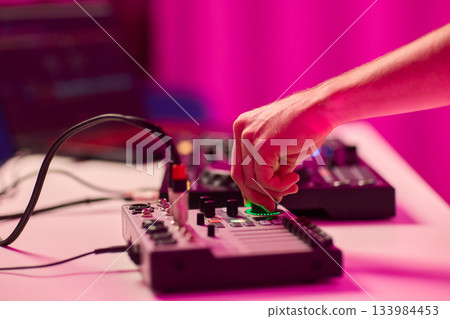 Closeup of tactile controls and vibrant patch cords in studio, Adjusting analog sequencing equipment with bright cables and warm ambient lighting in home studio 133984453