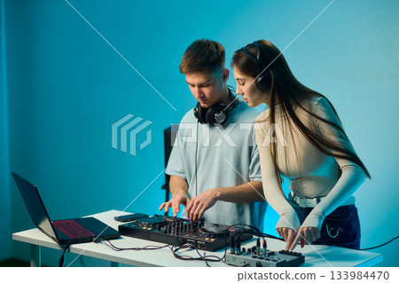 Music creators in studio, Studio session featuring musical synthesis and focused teamwork, Electronic music producers working together with various tools and instruments 133984470