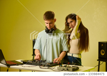 Music creators in studio, Studio session featuring musical synthesis and focused teamwork, Electronic music producers working together with various tools and instruments 133984473