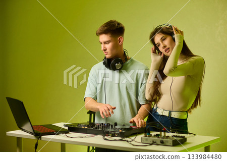 Music creators in studio, Studio session featuring musical synthesis and focused teamwork, Electronic music producers working together with various tools and instruments 133984480