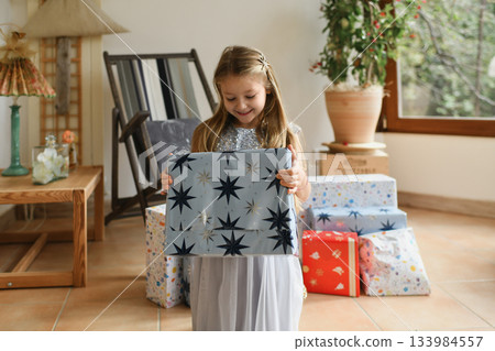 A girl unwraps the christmas presents 133984557
