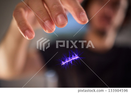 Hands manipulating metal spheres generate vibrant electrical plasma display, Laboratory scene showcasing coil discharging luminous sparks with scientific precision 133984596