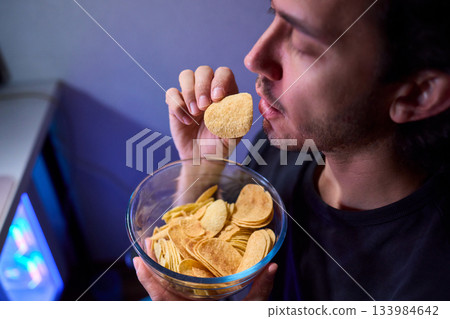 Programmer enjoying late night snack, Individual working alone in home office environment, Solitary male professional grubbing on sandwich during late hours at his desk 133984642
