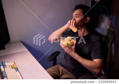 Programmer enjoying late night snack, Individual working alone in home office environment, Solitary male professional grubbing on sandwich during late hours at his desk 133984643