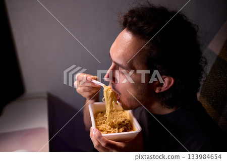 Live streaming snack, Content creator enjoys snack during livestream break, Casual moment captured during evening stream with ambient glow and home studio background 133984654
