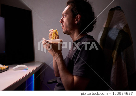 Live streaming snack, Content creator enjoys snack during livestream break, Casual moment captured during evening stream with ambient glow and home studio background 133984657