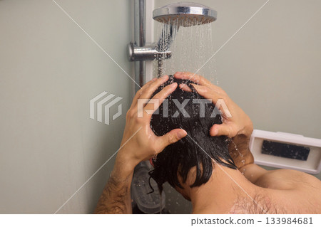 Close view of man washing hair thoroughly, Man under shower rinses hair closely while grooming himself, Detailed shot of man cleansing his hair with water under shower Close view of man washing hair thoroughly, Man under shower rinses hair closely while grooming himself, Detailed shot of man cleansing his hair with water under shower 133984681