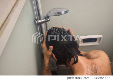 Close view of man washing hair thoroughly, Man under shower rinses hair closely while grooming himself, Detailed shot of man cleansing his hair with water under shower 133984682
