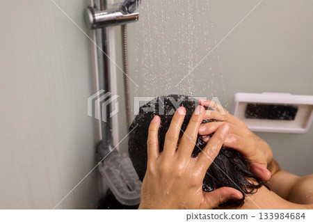 Close view of man washing hair thoroughly, Man under shower rinses hair closely while grooming himself, Detailed shot of man cleansing his hair with water under shower Close view of man washing hair thoroughly, Man under shower rinses hair closely while grooming himself, Detailed shot of man cleansing his hair with water under shower 133984684