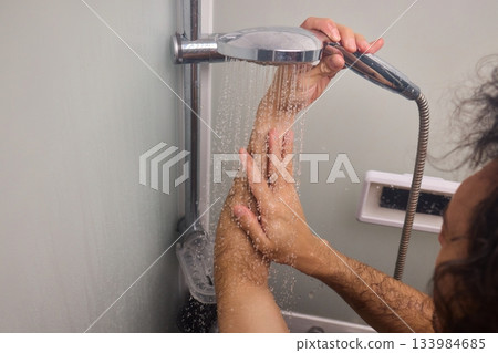Close view of man washing hair thoroughly, Man under shower rinses hair closely while grooming himself, Detailed shot of man cleansing his hair with water under shower Close view of man washing hair thoroughly, Man under shower rinses hair closely while grooming himself, Detailed shot of man cleansing his hair with water under shower 133984685