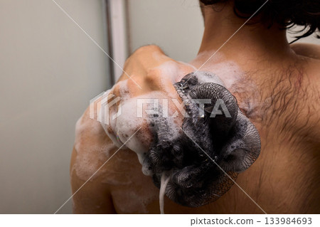 Close view of man washing hair thoroughly, Man under shower rinses hair closely while grooming himself, Detailed shot of man cleansing his hair with water under shower 133984693