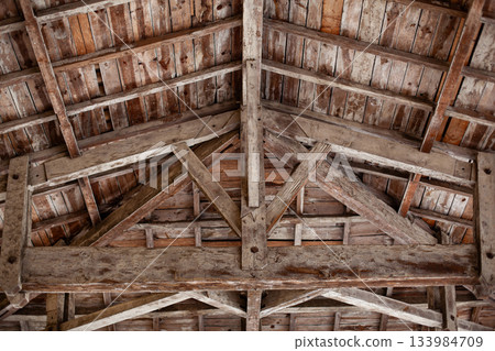 Weathered planks and beams under the roof of a barn 133984709