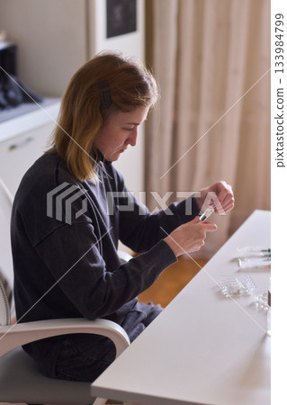 Self reliant woman handles morning pills in peaceful kitchen setting, Woman with cerebral palsy diligently manages her daily medication routine independently at home Self reliant woman handles morning pills in peaceful kitchen setting, Woman with cerebral palsy diligently manages her daily medication routine independently at home 133984799