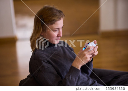 Casual female gamer with cerebral palsy, Relaxed woman with gaming controller, Young woman plays video game comfortably at home, Female gamer intently engaging with console in cozy living space Casual female gamer with cerebral palsy, Relaxed woman with gaming controller, Young woman plays video game comfortably at home, Female gamer intently engaging with console in cozy living space 133984830