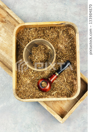 Smoking pipe with tobacco on a table. 133984870