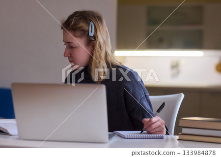 Determined individual with cerebral palsy immersed in educational activities indoors, Courageous woman with cerebral palsy concentrates on studying at home with dedication 133984878