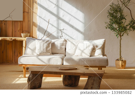 Modern minimalist interior of living room with beige sofa, rustic wooden table in natural sunlight Modern minimalist interior of living room with beige sofa, rustic wooden table in natural sunlight 133985082