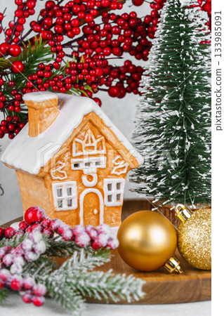 Gingerbread style ceramic Christmas house with ornaments, holly berries and snowy winter tree 133985091