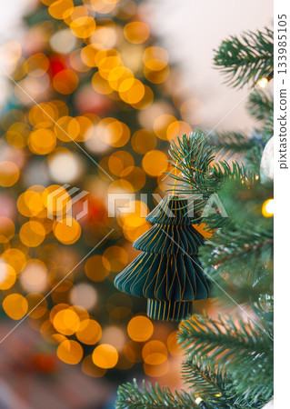 Dark green Christmas tree paper ornament with glowing golden bokeh holiday lights background 133985105