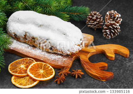 Traditional Christmas Stollen, sweet fruit loaf with sugar icing on wooden board and festive decor Traditional Christmas Stollen, sweet fruit loaf with sugar icing on wooden board and festive decor 133985116