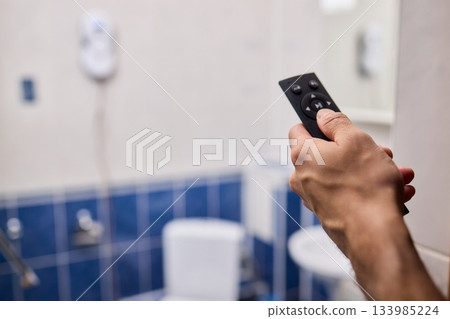 Smart robot performing quick hygienic maintenance in bathroom space, Modern robotic cleaner diligently scrubbing grout lines adjacent to toilet in bright tiled room 133985224