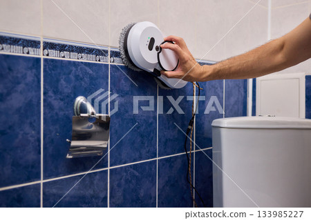 Smart robot performing quick hygienic maintenance in bathroom space, Modern robotic cleaner diligently scrubbing grout lines adjacent to toilet in bright tiled room Smart robot performing quick hygienic maintenance in bathroom space, Modern robotic cleaner diligently scrubbing grout lines adjacent to toilet in bright tiled room 133985227