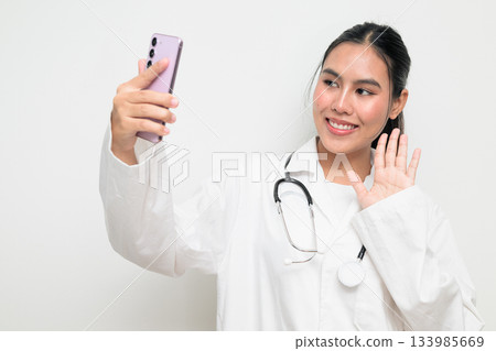 Woman Doctor with Stethoscope in White Uniform on Plain Background Using Phone Taking Selfie Woman Doctor with Stethoscope in White Uniform on Plain Background Using Phone Taking Selfie 133985669
