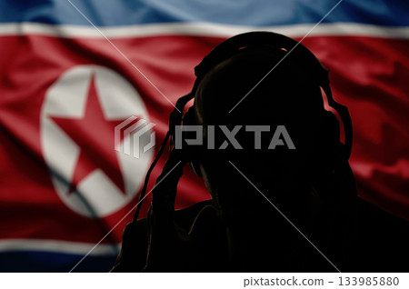 Silhouette of a man in headphones, secret agent eavesdropping, spy and scout, the flag of North Korea, backlight Silhouette of a man in headphones, secret agent eavesdropping, spy and scout, the flag of North Korea, backlight 133985880