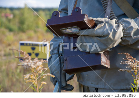 Military dosimeter measures radiation on the background of the sign of radiation hazard, military dosimeter, close-up 133985886