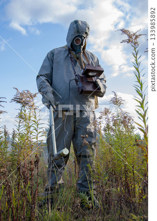 Military dosimetrist measures radiation, ACRID SMOKE after the EXPLOSION, chemical protective suit and gas mask, 133985892
