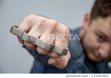 A man strikes a brass knuckles on a light background, a street gang of hooligans 133985902