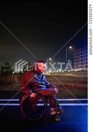 Upset young disabled man in wheelchair in rgb neon light deeply thinking, dealing with stress. 133985974