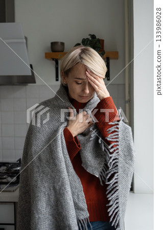 Middle aged woman with painful expression suffering from headache and high temperature caused by flu Middle aged woman with painful expression suffering from headache and high temperature caused by flu 133986028