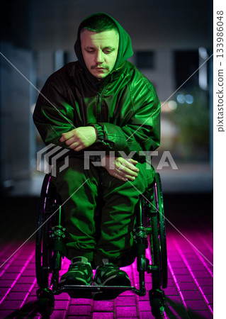 Disabled man in wheelchair in color neon rgb light expressing mental health struggles and heartbreak Disabled man in wheelchair in color neon rgb light expressing mental health struggles and heartbreak 133986048