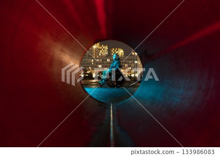 Young disabled man in rgb color light sits in wheelchair looking at city lights, thinking about life Young disabled man in rgb color light sits in wheelchair looking at city lights, thinking about life 133986083