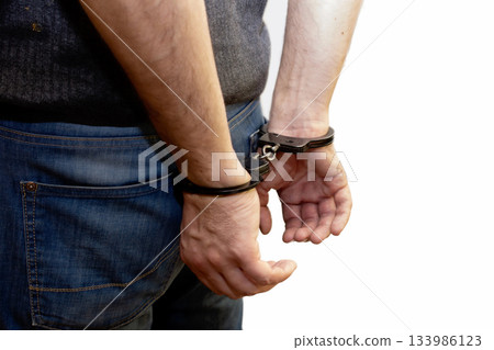 The man is handcuffed, his hands behind his back, the caught criminal, the detention of the offender, on a white background, isolate 133986123