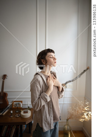 Thoughtful female place palms on torso regulate inhalation and exhalation in mindful pause at home Thoughtful female place palms on torso regulate inhalation and exhalation in mindful pause at home 133986138