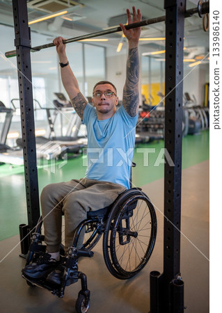 Purposeful wheelchair man do pull up in gym for upper torso development, disabled male sports 133986140
