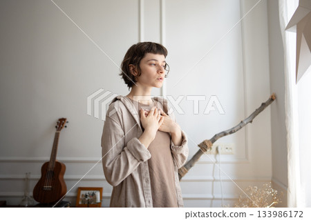 Calm young woman put hands on chest to guide deep breath and reflection, stress relief after panic 133986172