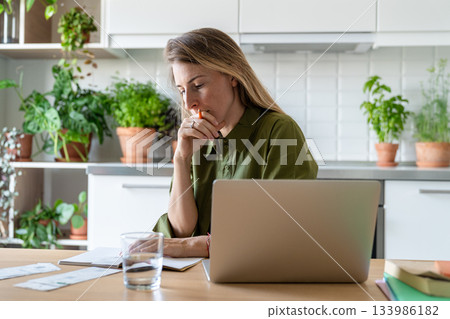 Worried middle aged woman writing expenses and income in financial dairy, planning home budget. 133986182